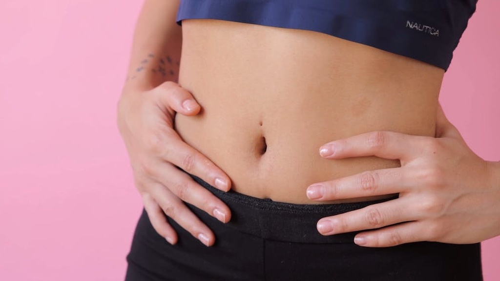 Pessoa com as mãos na barriga/quadril, com um cropped e umbigo amostra, simbolizando a dúvida se tampar o umbigo funciona