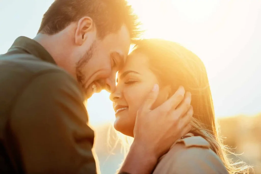 Casal prestes a dar um beijo em um local ensolarado.