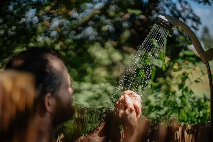 Homem tomando uma ducha em meio à natureza