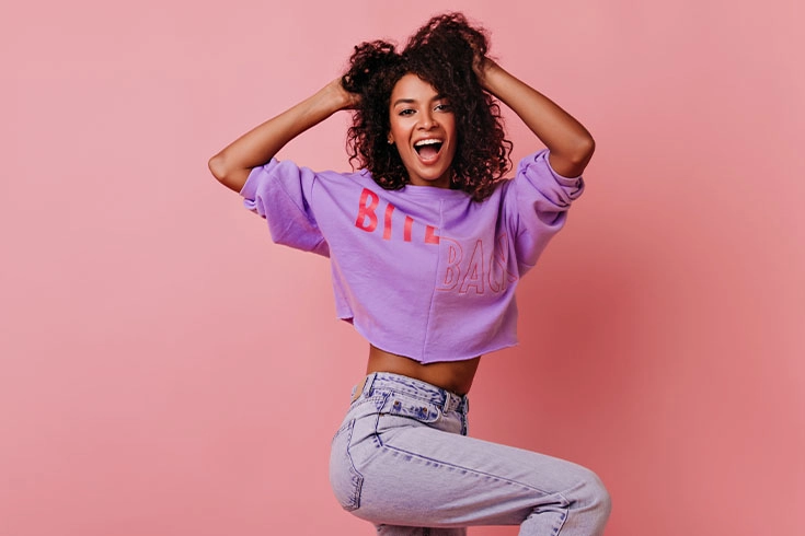 Mulher com cropped violeta sobre fundo rosa