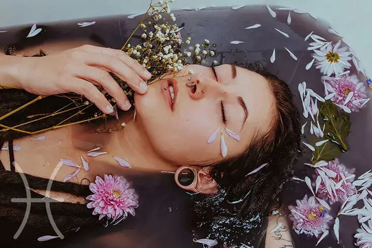 Mulher deitada em banheira com muitas pétalas de flores