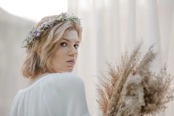 Mulher representando o signo de virgem, segurando ramos, com flores no cabelo