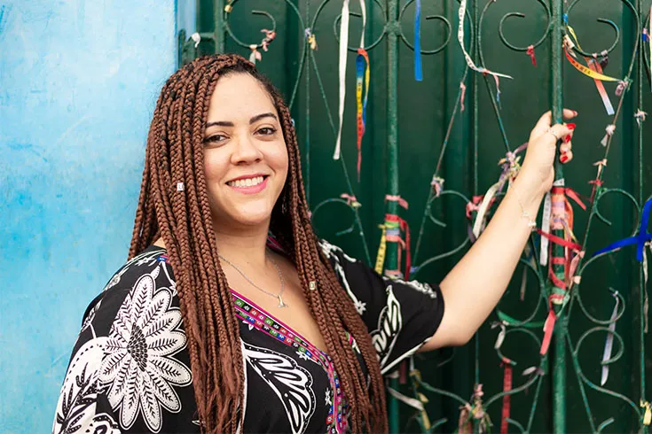 Mulher posando ao lado de um portão com fitas coloridas