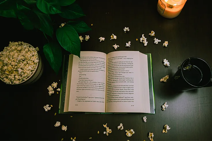 Livro aberto, com vela e pipocas