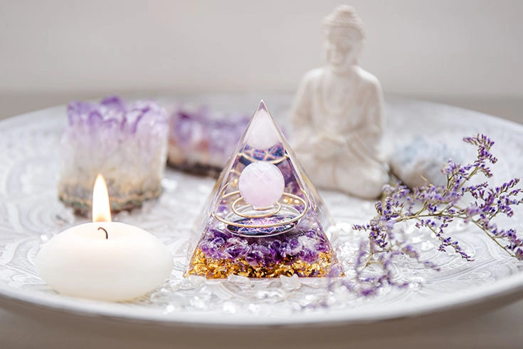 Mesa clara com orgonite, velas, imagem de buda e ametistas