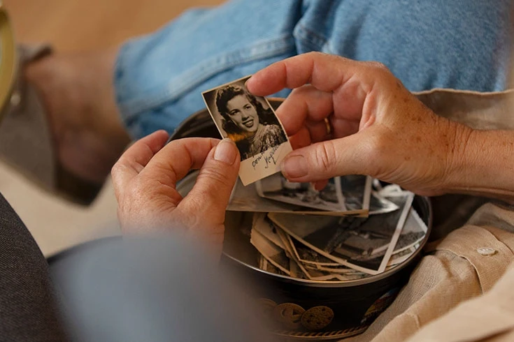 Pessoa segurando fotos antigas com as duas mãos.