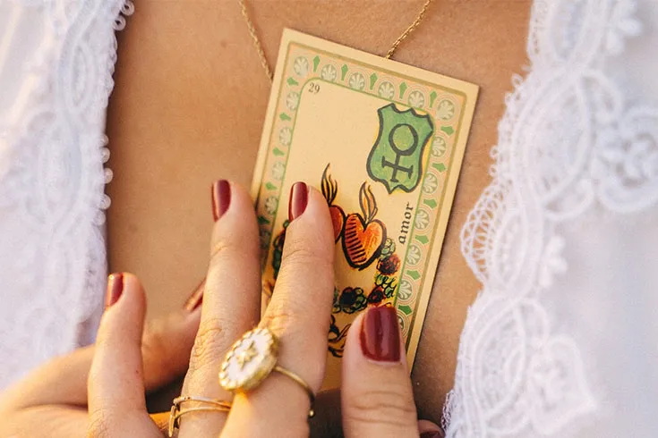 Mãos femininas pressionando uma carta de tarot com o corpo.