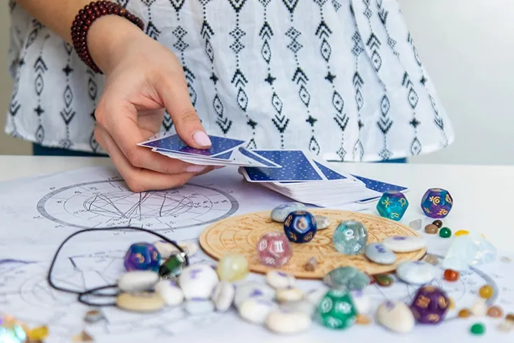 Mão feminina mexendo em um baralho disposto em cima da mesa
