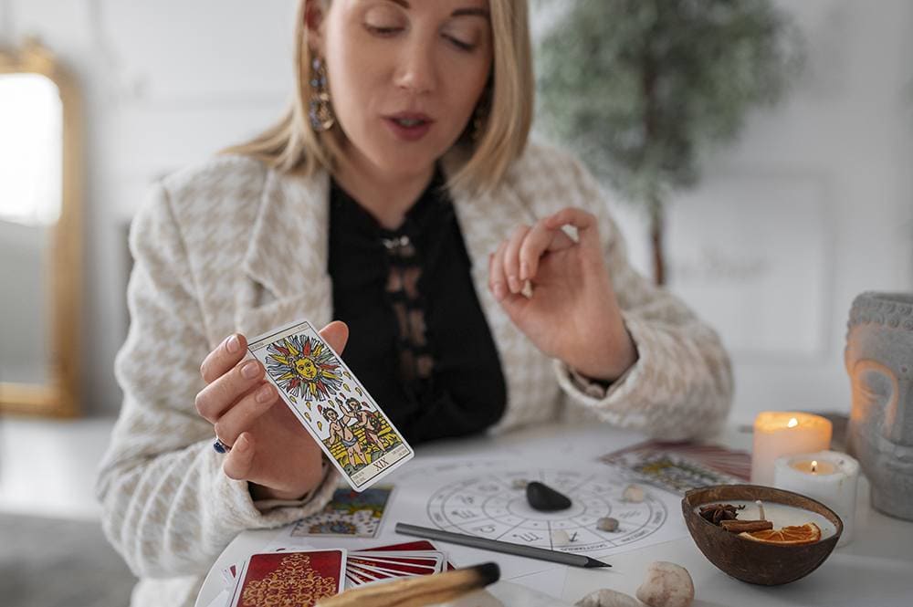 Taróloga segurando na mão direita a carta do Tarot Sol enquanto faz uma consulta de Tarot Online no Astrocentro