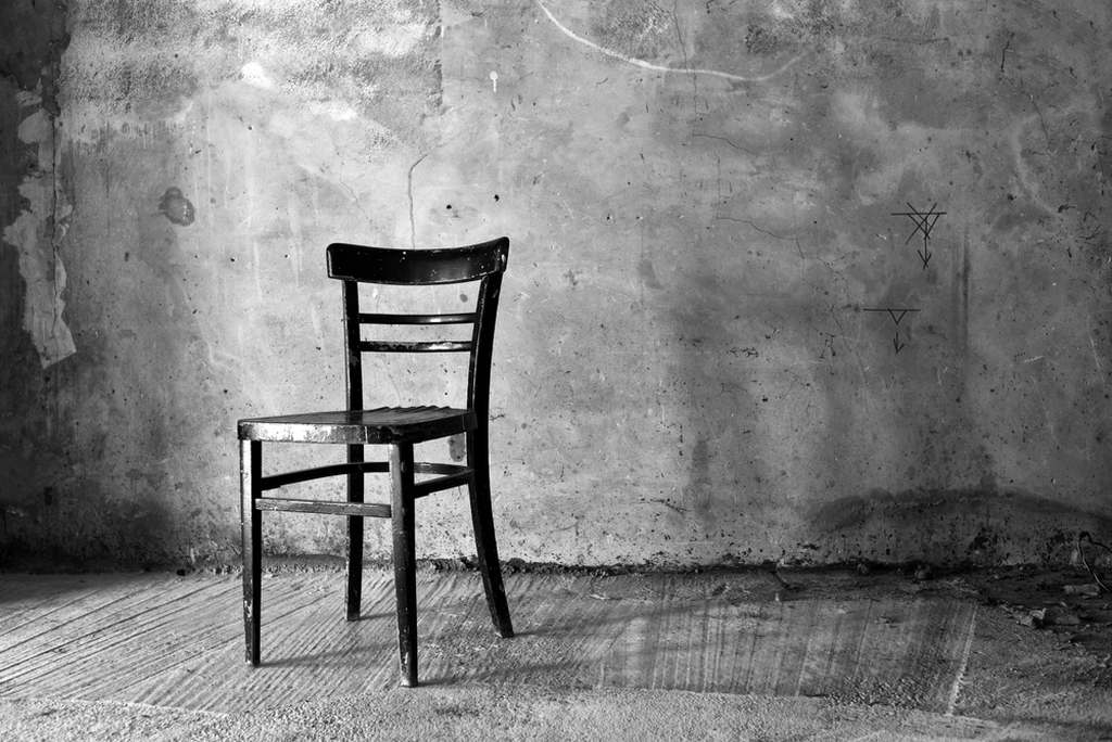Uma cadeira num cômodo vazio, sombrio, simbolizando o que significa sonhar com sequestro