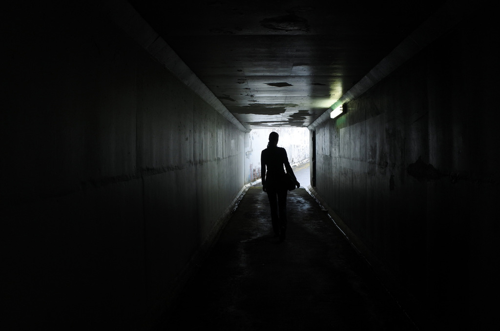 Mulher em pé num túnel escuro e estreito, simbolizando sonhar com cativeiro
